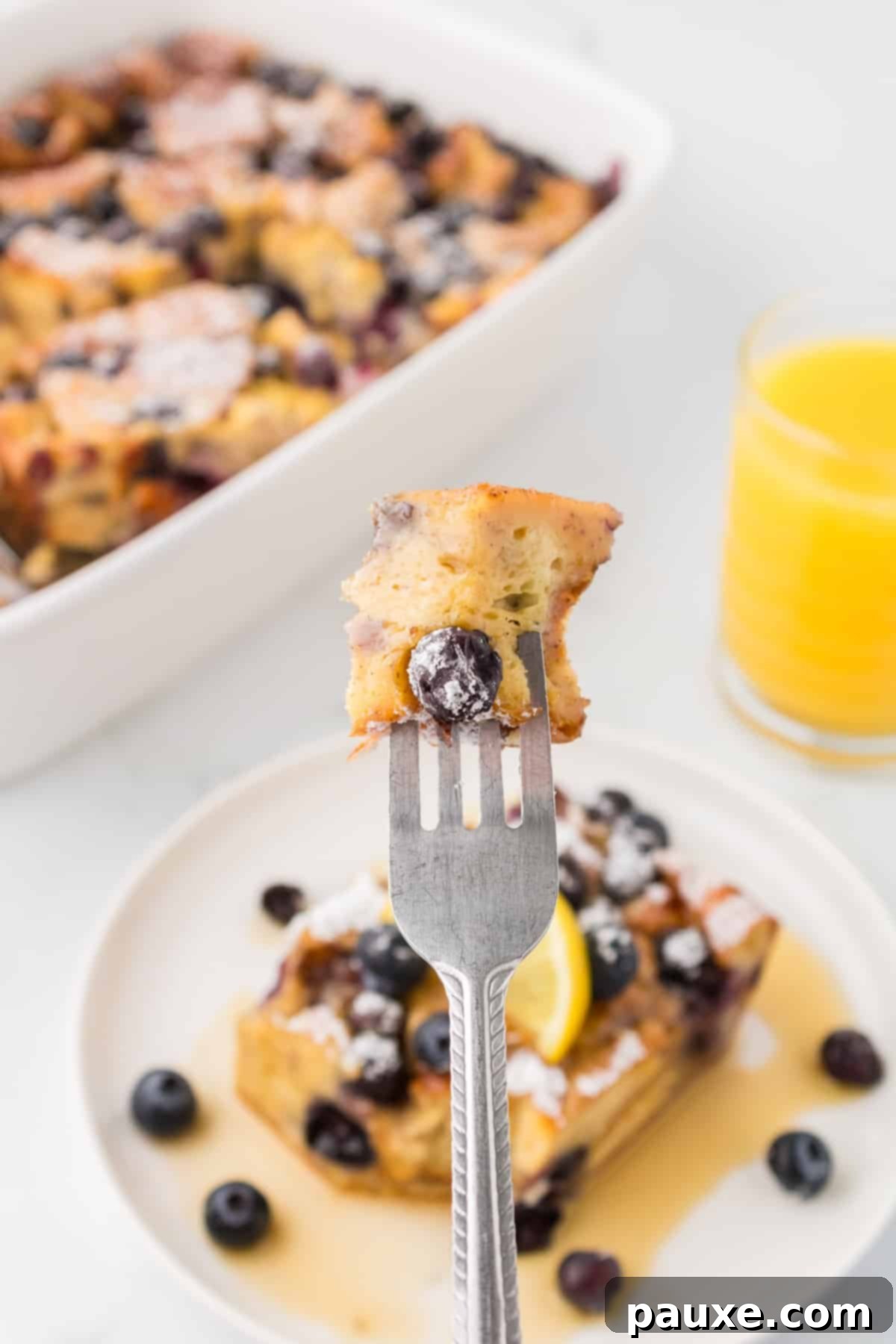 Overnight Brioche French Toast Bake 14 A fork holding a single, golden-brown piece of brioche French toast, showing its fluffy interior and inviting texture, ready to be enjoyed.