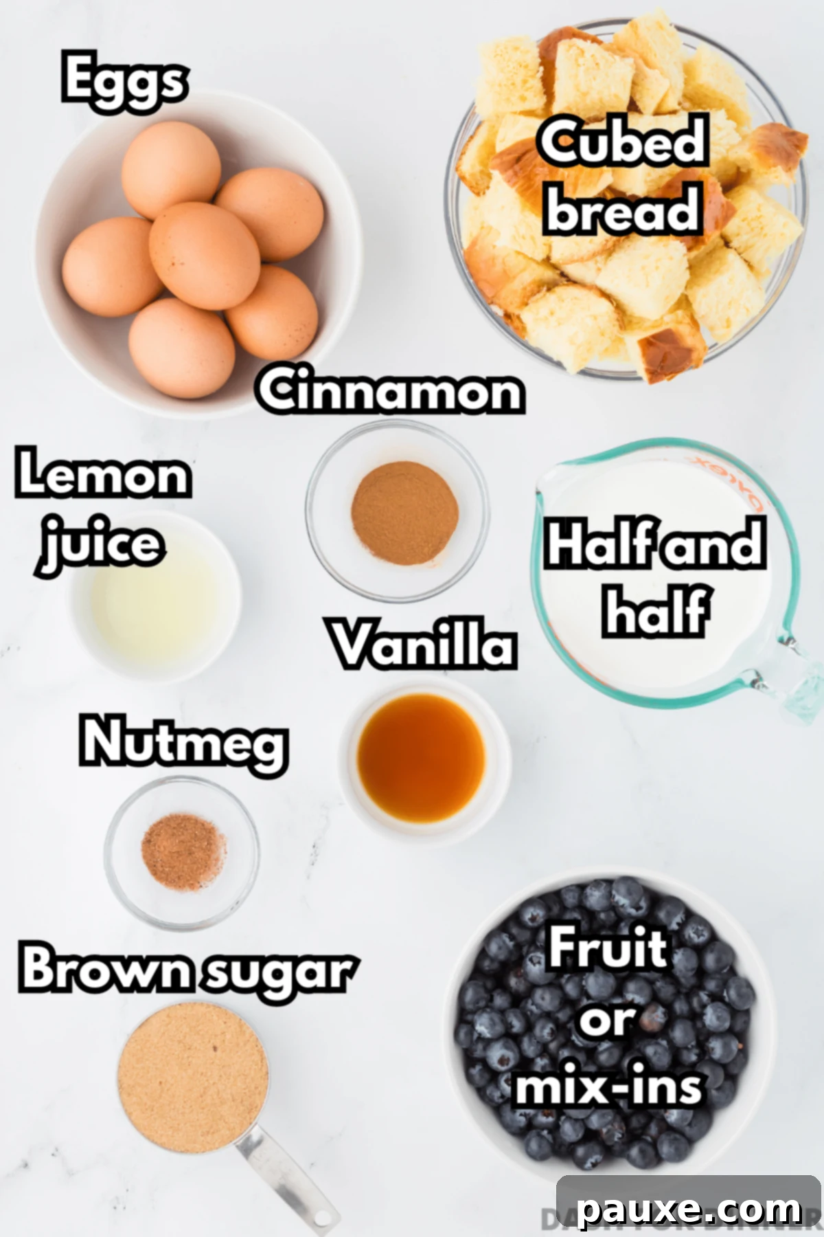 Overnight Brioche French Toast Bake 3 A collection of fresh ingredients laid out on a kitchen counter, including a loaf of brioche bread, eggs, a carton of half and half, a bowl of fresh blueberries, brown sugar, vanilla extract, cinnamon, and nutmeg, all ready to be used for the French toast casserole.