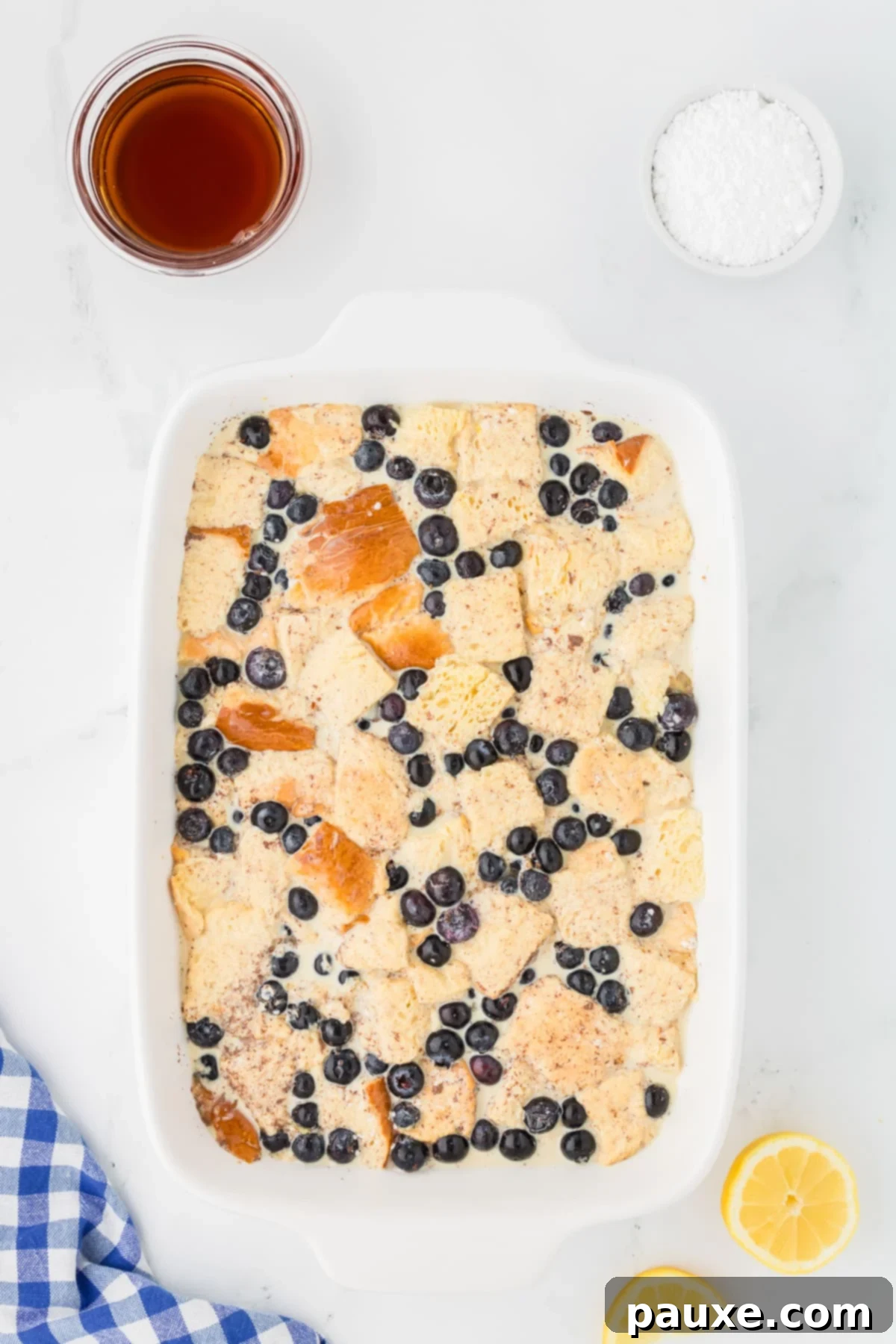 Overnight Brioche French Toast Bake 9 A baking dish filled with brioche bread cubes and blueberries, thoroughly soaked in the custard mixture and covered with plastic wrap, ready for refrigeration.