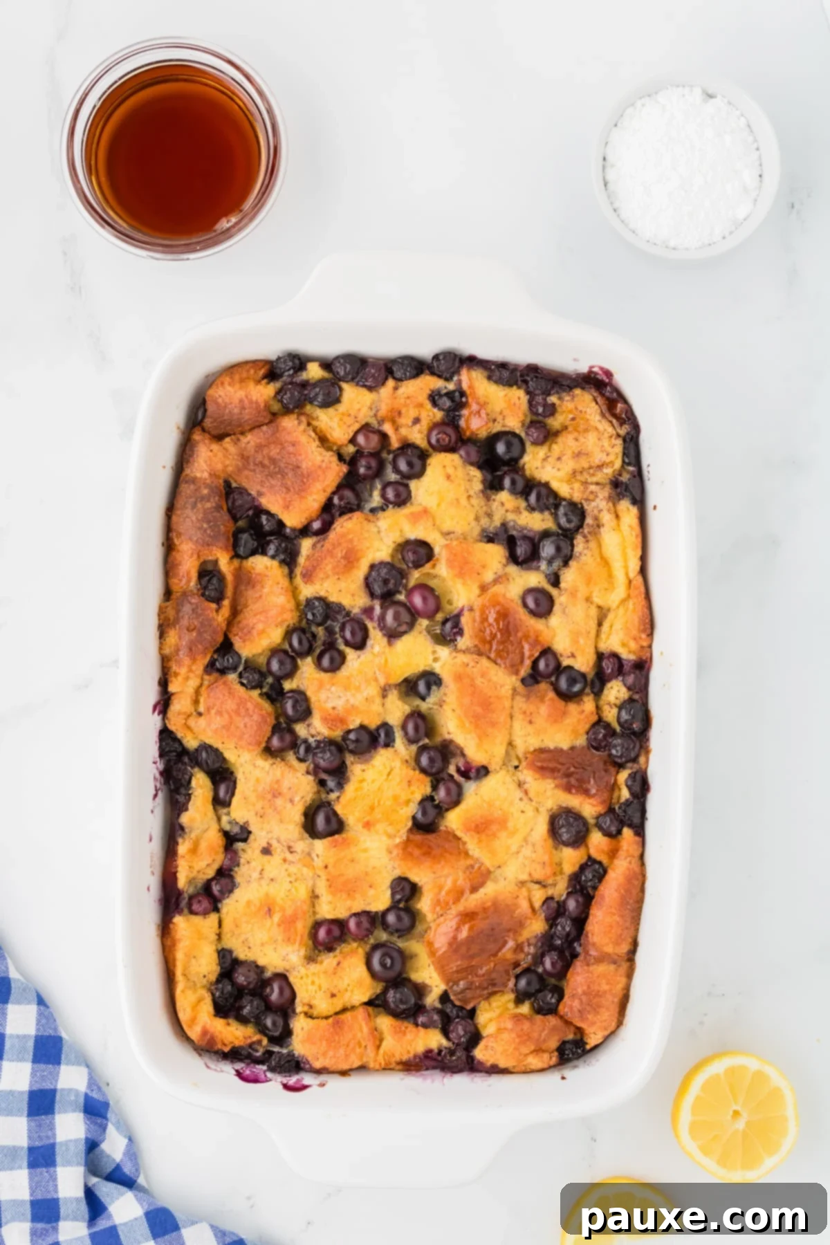 Overnight Brioche French Toast Bake 10 A baked Brioche French Toast Casserole in a baking dish, golden brown on top and generously studded with blueberries, fresh out of the oven.