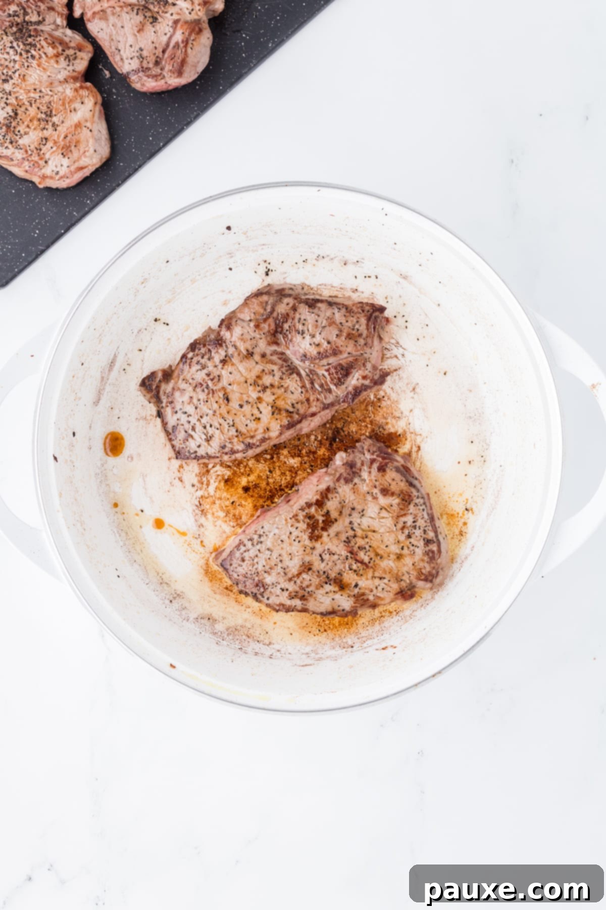 Easy Slow Cooker Pepper Steak 5 Steaks that are browning in a Dutch Oven, developing a rich, dark crust.