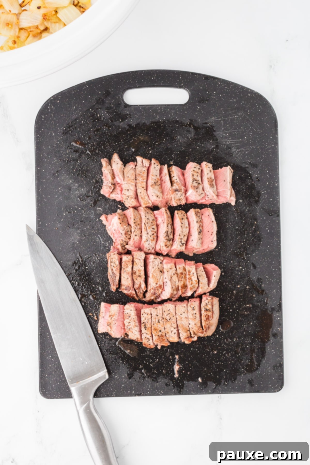 Easy Slow Cooker Pepper Steak 6 A cutting board with browned beef cut into strips, ready for the slow cooker.
