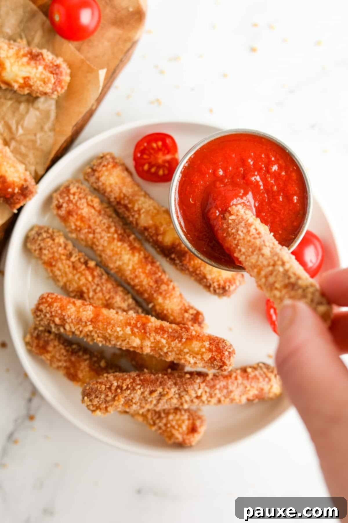 Crispy Air Fryer Halloumi Fries 2 A plate with golden brown halloumi fries, with one being dipped into a vibrant pizza sauce.