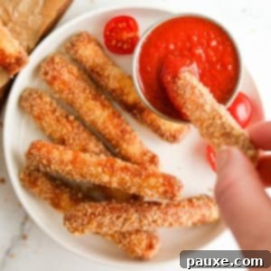 Crispy Air Fryer Halloumi Fries 13 A breaded halloumi fry being dipped into pizza sauce, highlighting its crispy texture.