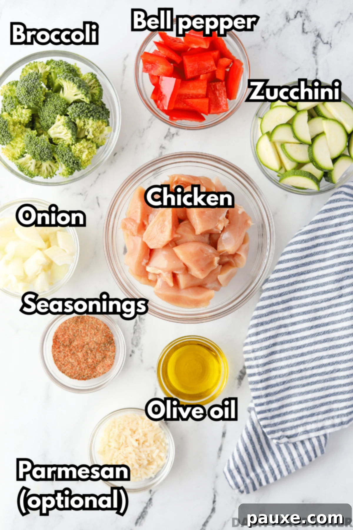 Crispy Air Fryer Chicken and Veggies 3 An overhead shot showcasing all the fresh ingredients needed for air fryer chicken and veggies: raw chicken, vibrant broccoli florets, red bell pepper, zucchini, onion, olive oil, and a selection of dry seasonings.