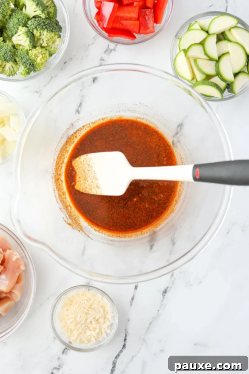 Crispy Air Fryer Chicken and Veggies 4 A bowl with a silicone spatula stirring a blend of seasonings and olive oil together.
