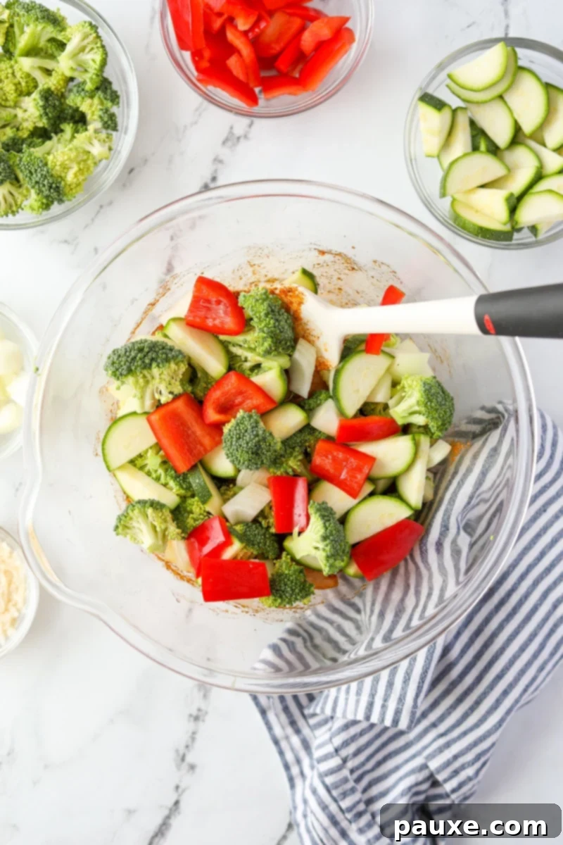 Crispy Air Fryer Chicken and Veggies 6 A large bowl containing raw broccoli florets, chopped bell peppers, zucchini, and onions, ready to be mixed with the chicken.