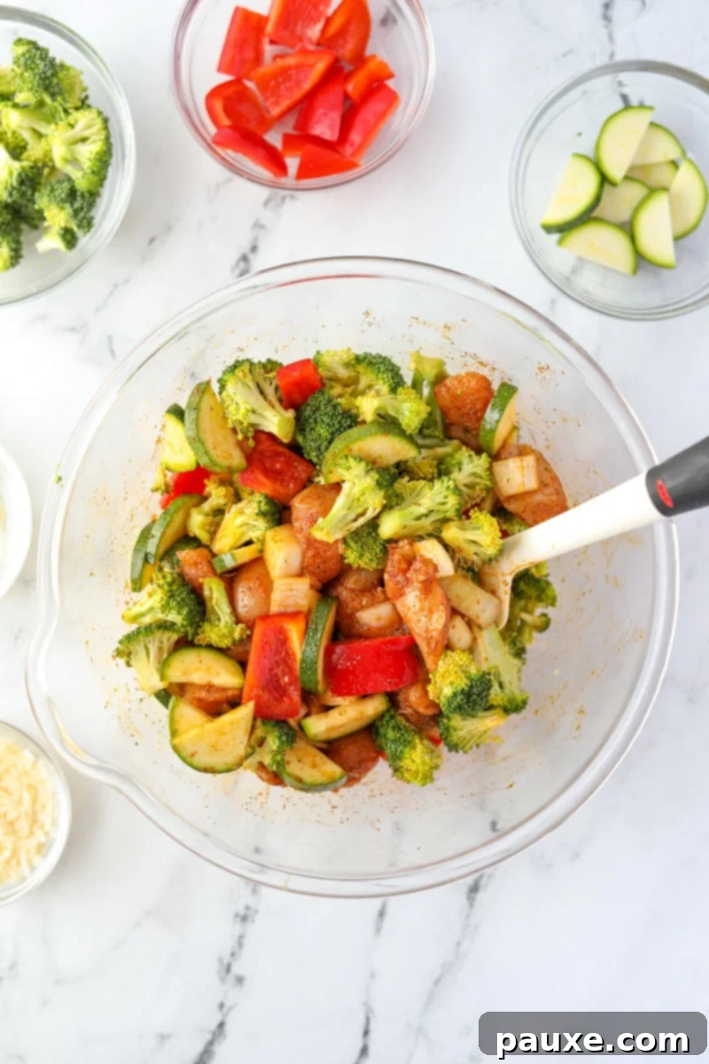 Crispy Air Fryer Chicken and Veggies 7 A medley of chicken and vegetables fully tossed and coated with the seasoning and oil mixture in a large bowl.