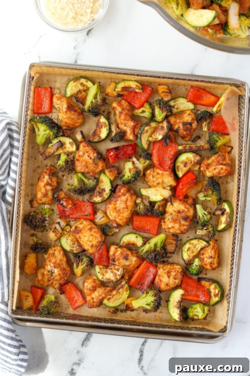 Crispy Air Fryer Chicken and Veggies 9 A close-up of an air fryer basket with chicken and vegetables spread out in an even layer, midway through cooking, showing a golden brown color.