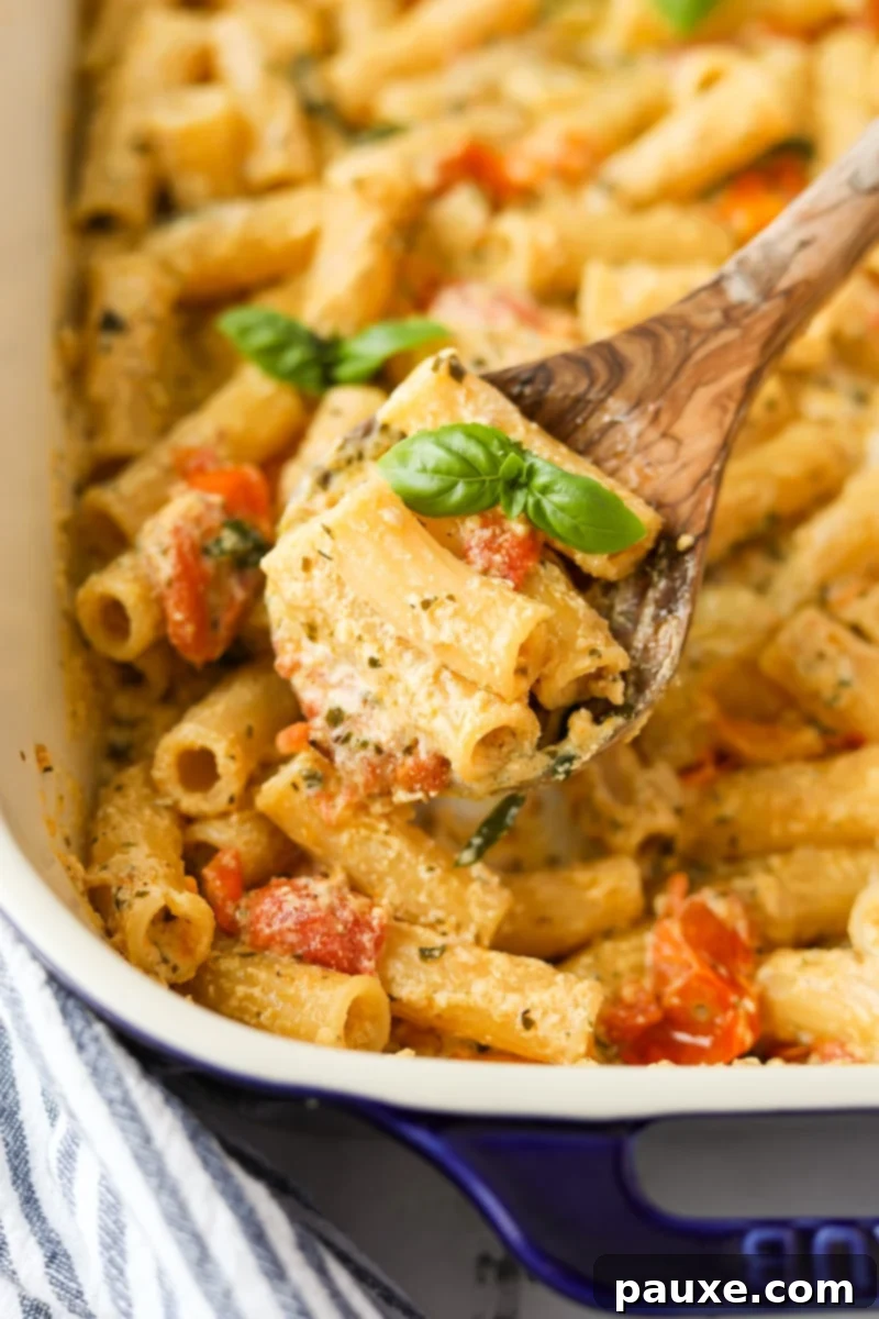 Creamy Boursin Pasta Bake 11 A spoon scooping a portion of the creamy Boursin pasta from a baking dish, highlighting its rich texture.