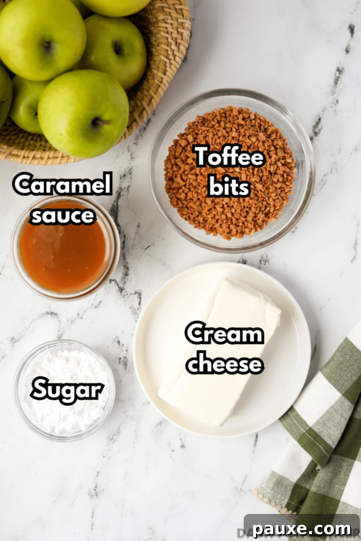 Irresistible Caramel Apple Delight 3 A beautifully arranged flat lay of the four essential ingredients needed to make homemade caramel apple dip: a jar of rich caramel sauce, a block of softened cream cheese, a small bowl of crunchy toffee bits, and a bowl of fine powdered sugar.