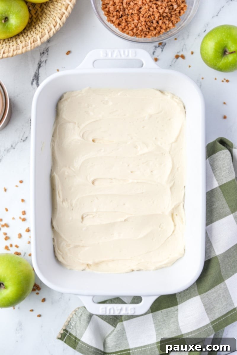 Irresistible Caramel Apple Delight 6 A medium baking dish filled with a perfectly smooth, even, and pristine layer of the cream cheese mixture at its base.