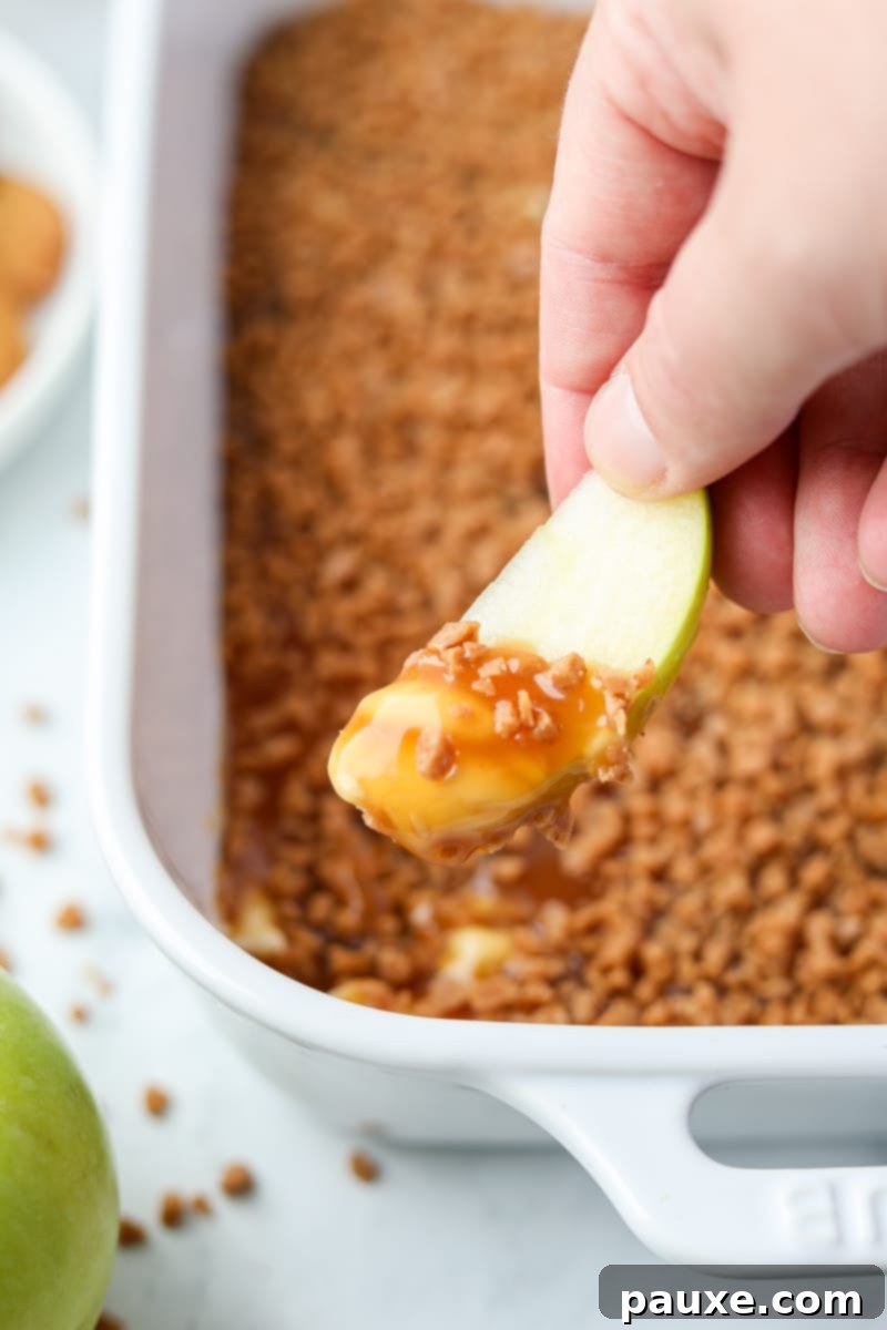 Irresistible Caramel Apple Delight 10 Multiple freshly sliced apple pieces arranged invitingly around a dish of caramel and toffee dip, ready for a delicious treat.