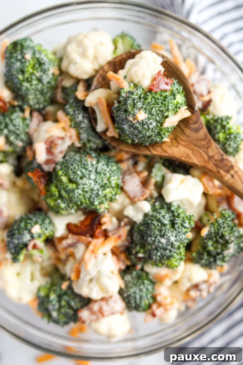 Creamy Amish Broccoli Salad 11 A large wooden serving spoon retrieving a generous portion of creamy Amish broccoli salad from a rustic bowl, showcasing its fresh ingredients and inviting texture.