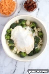 Creamy Amish Broccoli Salad 15 A bowl with cauliflower, broccoli, and a cream dressing piled on top.