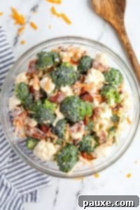 Creamy Amish Broccoli Salad 17 A bowl filled with broccoli and cauliflower salad, topped with cheese and bacon.