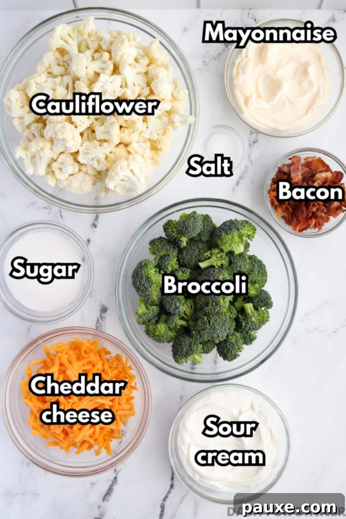 Creamy Amish Broccoli Salad 3 A flat lay photograph showcasing all the fresh ingredients needed for Amish broccoli salad, including vibrant green broccoli florets, white cauliflower florets, a block of sharp cheddar cheese, strips of raw bacon, a jar of mayonnaise, a tub of sour cream, and a bowl of sugar, against a rustic background.
