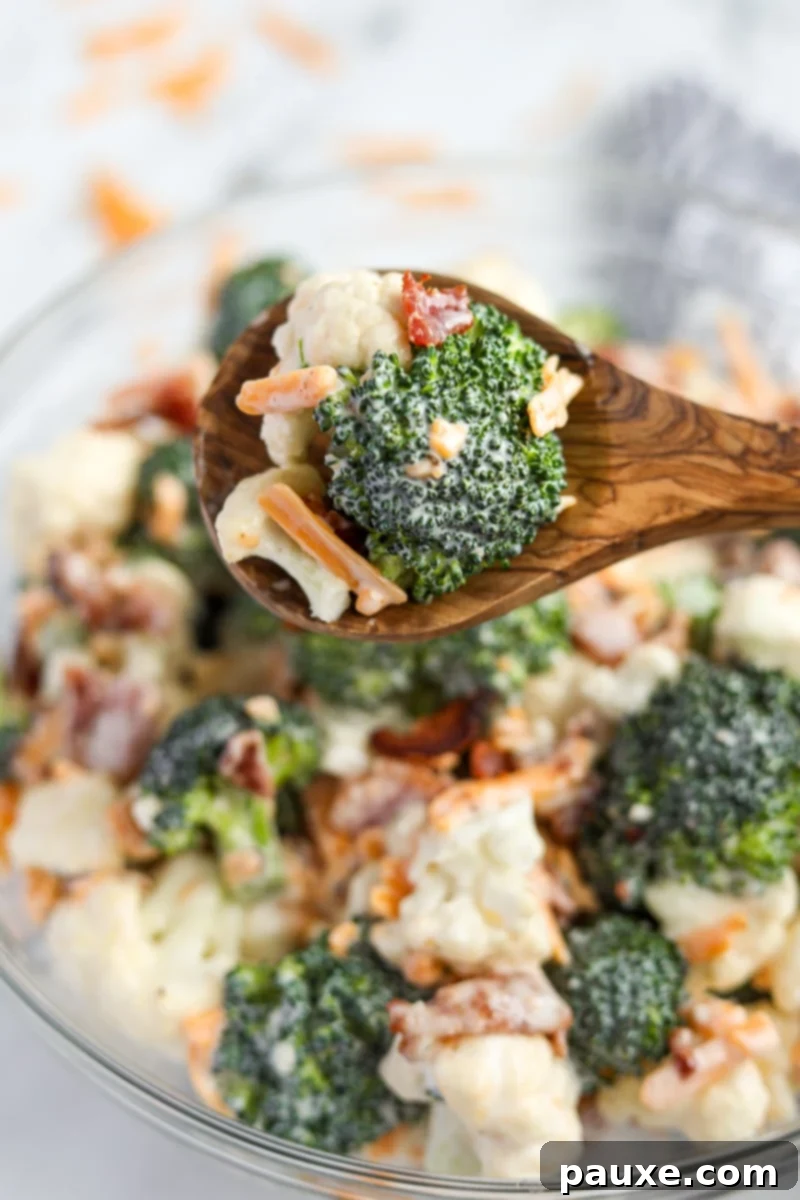 Creamy Amish Broccoli Salad 9 A single serving of creamy Amish broccoli salad carefully scooped onto a rustic wooden spoon, showing the blend of florets, cheese, and bacon, ready to be enjoyed.