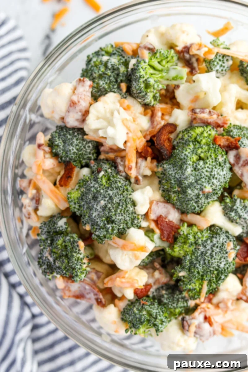 Creamy Amish Broccoli Salad 10 A vibrant bowl of Amish broccoli salad, beautifully garnished with extra shredded cheddar cheese and crispy bacon bits on top, highlighting its rich and inviting textures.