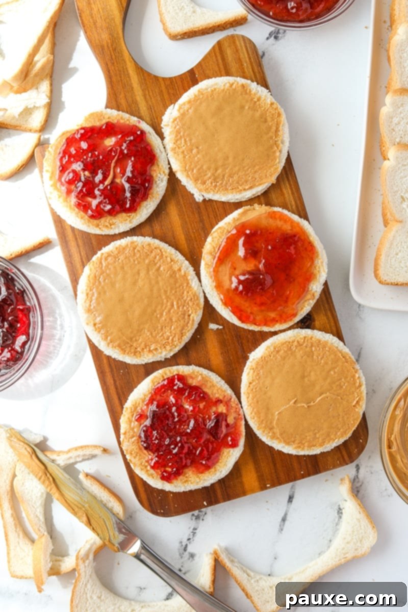 DIY Crustless Sandwich Pockets 8 Carefully spreading a thin layer of strawberry jam over the peanut butter on a bread round, ensuring not to reach the edges.