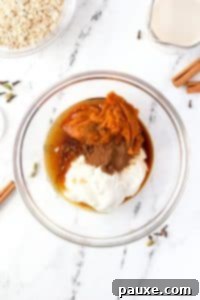 Pumpkin Spice Overnight Oats 15 A bowl filled with greek yogurt, pumpkin, maple syrup, and spices.