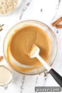 Pumpkin Spice Overnight Oats 16 A silicone spatula stirring a pumpkin colored liquid.