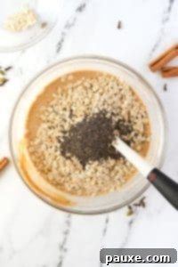 Pumpkin Spice Overnight Oats 17 Adding oats and chia seeds to a bowl of pumpkin colored liquid.