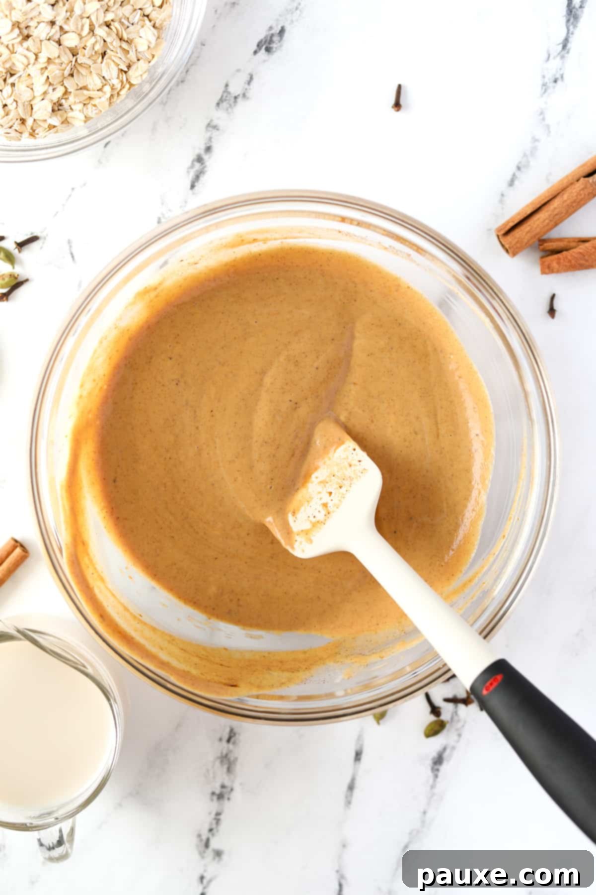 Pumpkin Spice Overnight Oats 5 A silicone spatula stirring a pumpkin colored liquid.