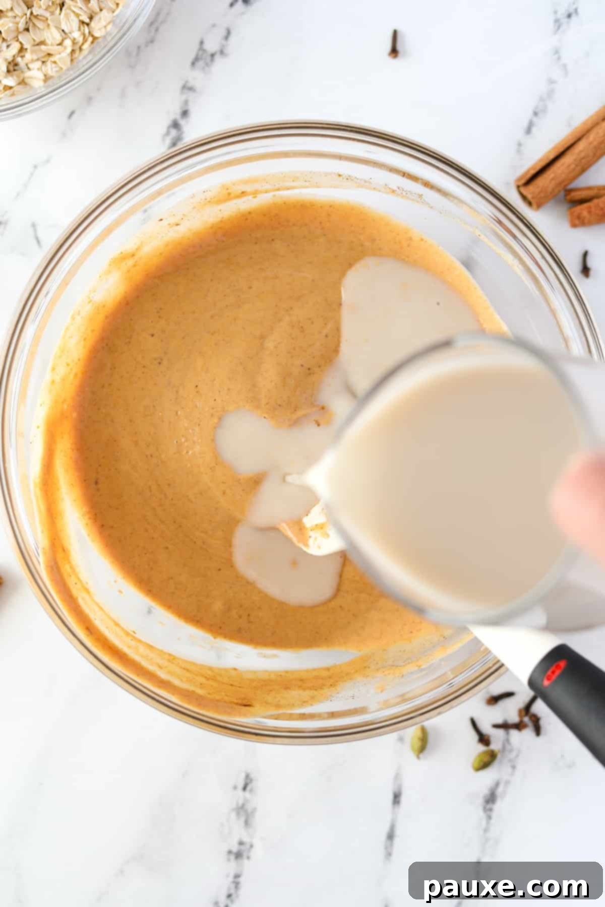 Pumpkin Spice Overnight Oats 6 Adding cashew milk to a bowl full of pumpkin colored liquid.