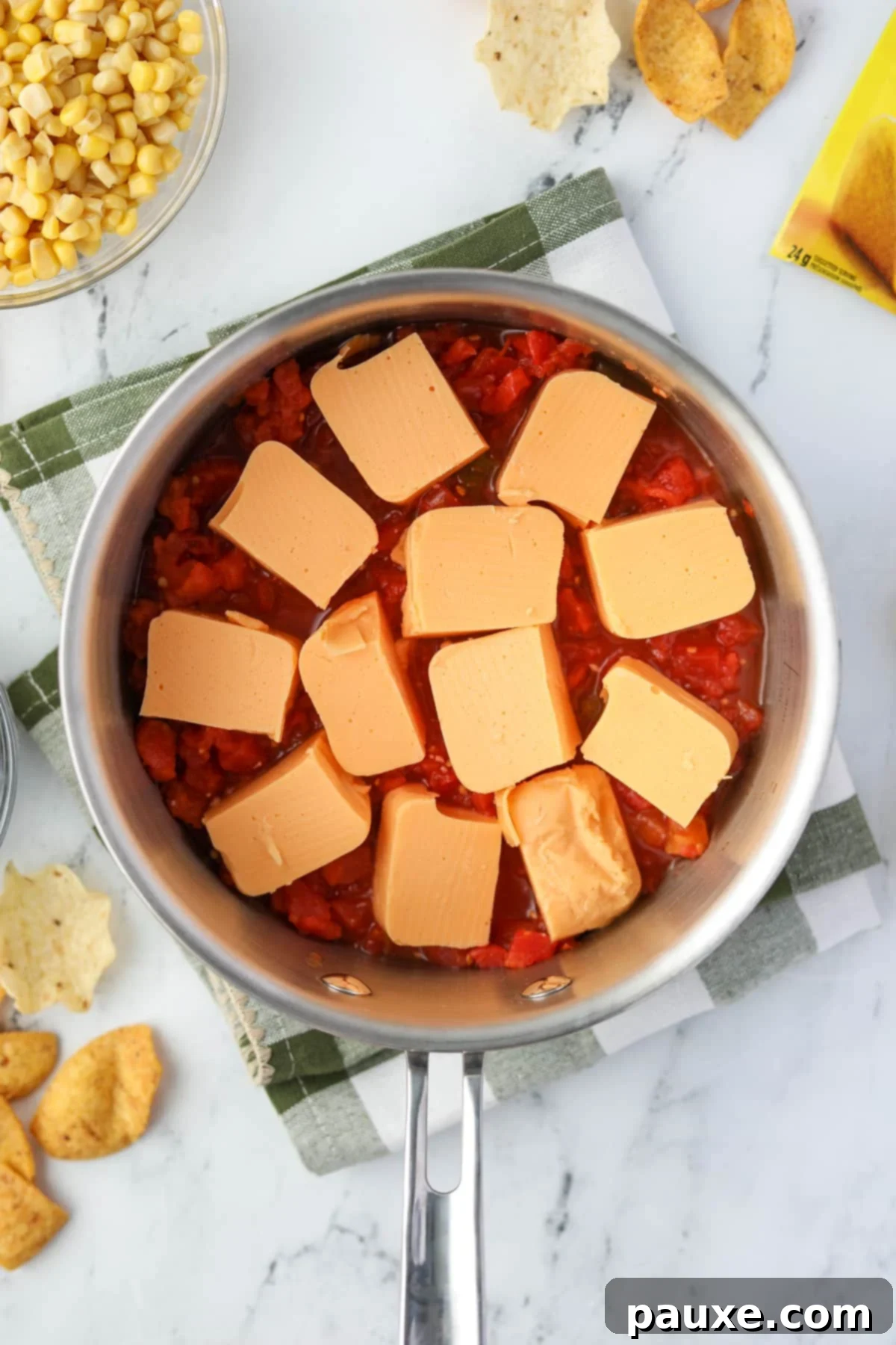 Zesty Fiesta Dip 4 A saucepan containing cubed Velveeta cheese and a can of undrained Rotel diced tomatoes and green chilies, ready to be melted.