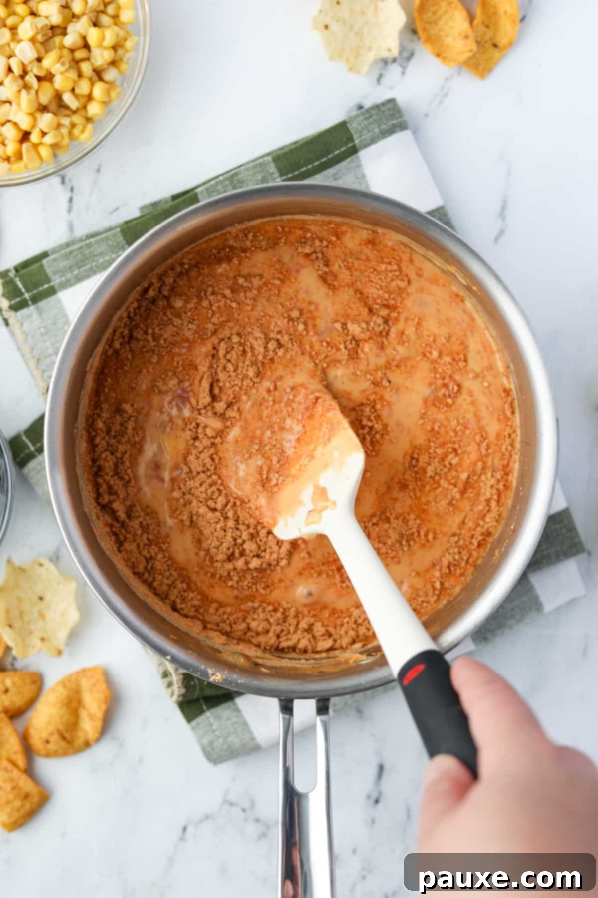 Zesty Fiesta Dip 7 The taco seasoning being stirred thoroughly into the creamy Rotel dip to distribute the flavor evenly.