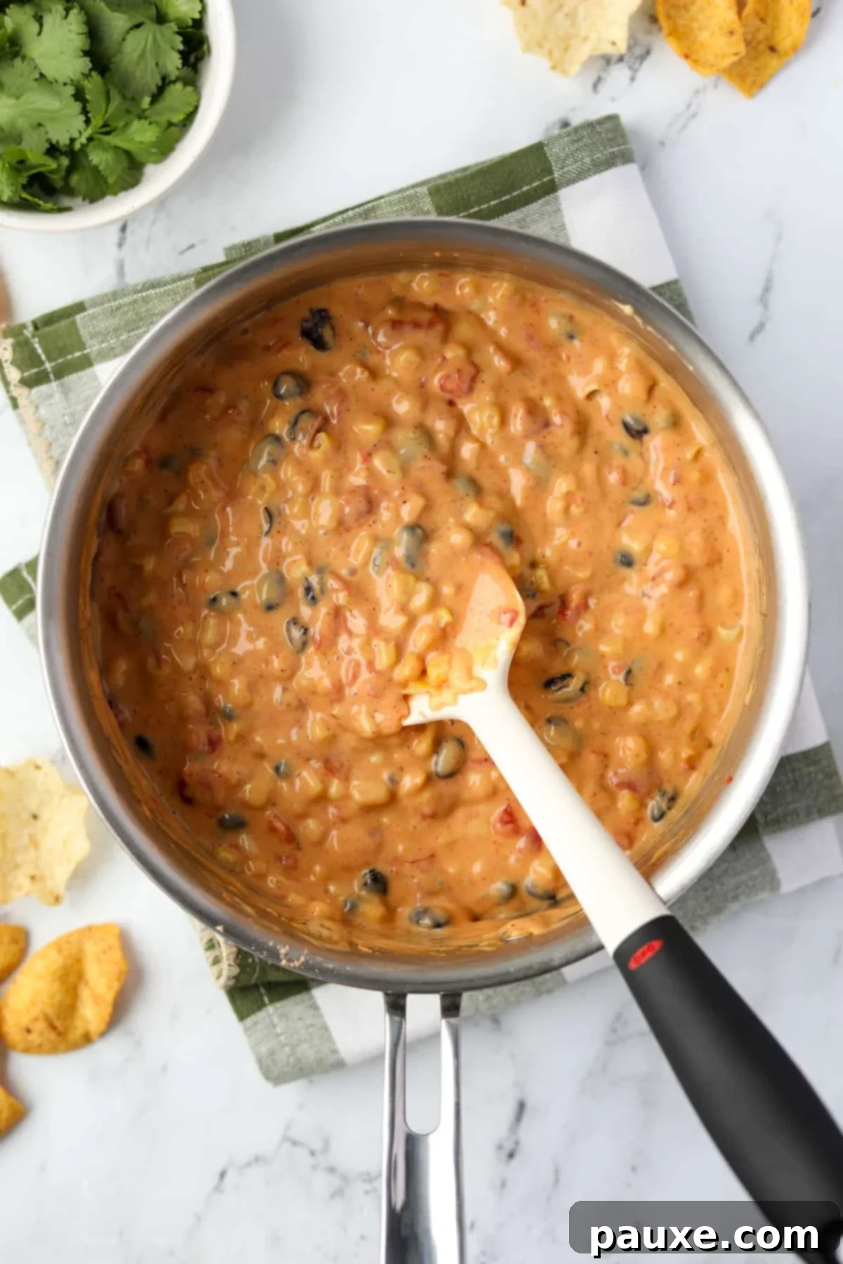 Zesty Fiesta Dip 9 The Velveeta, Rotel, corn, and black beans being stirred together in a saucepan until warmed through.