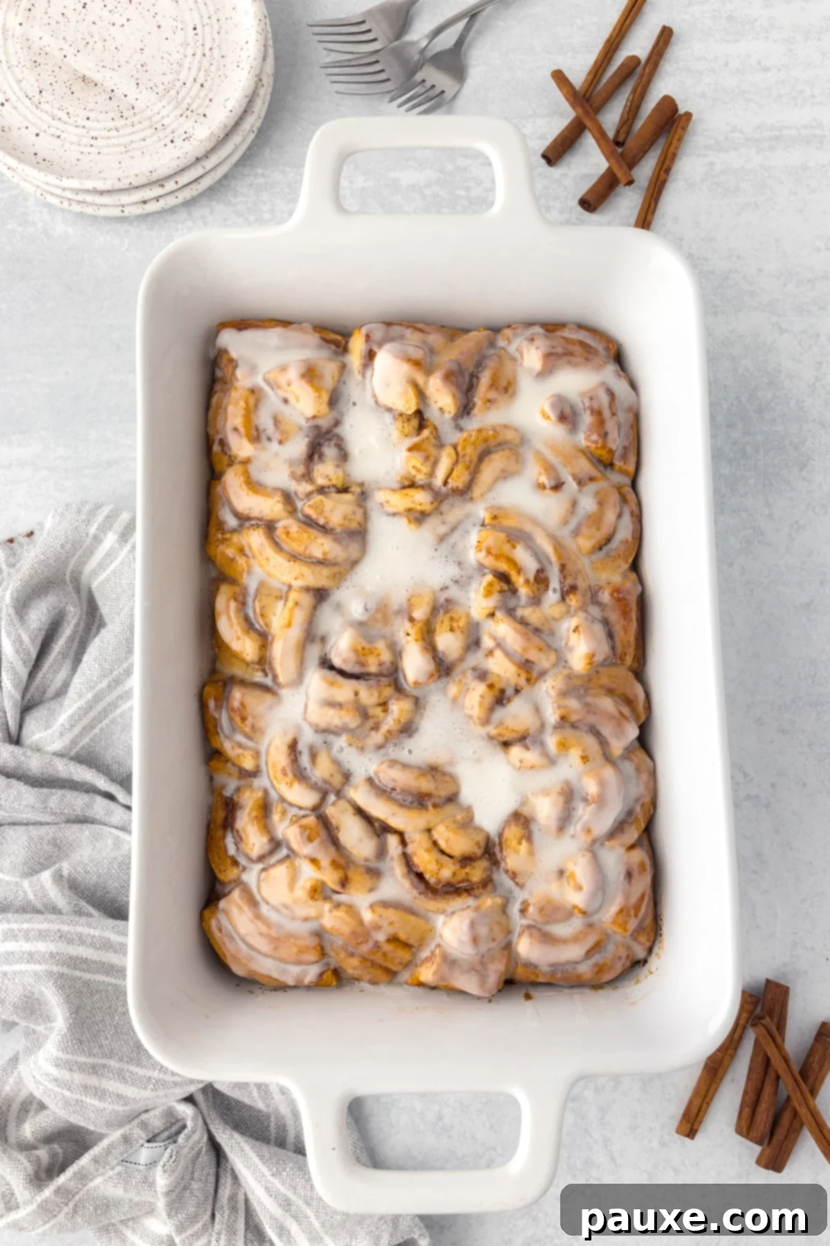 Gooey Cinnamon Bliss Bake 11 The finished cinnamon roll casserole in a baking dish, glistening with a thick layer of white icing.