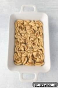 Gooey Cinnamon Bliss Bake 17 A casserole dish with cinnamon rolls sliced and fit into the dish in an even layer.