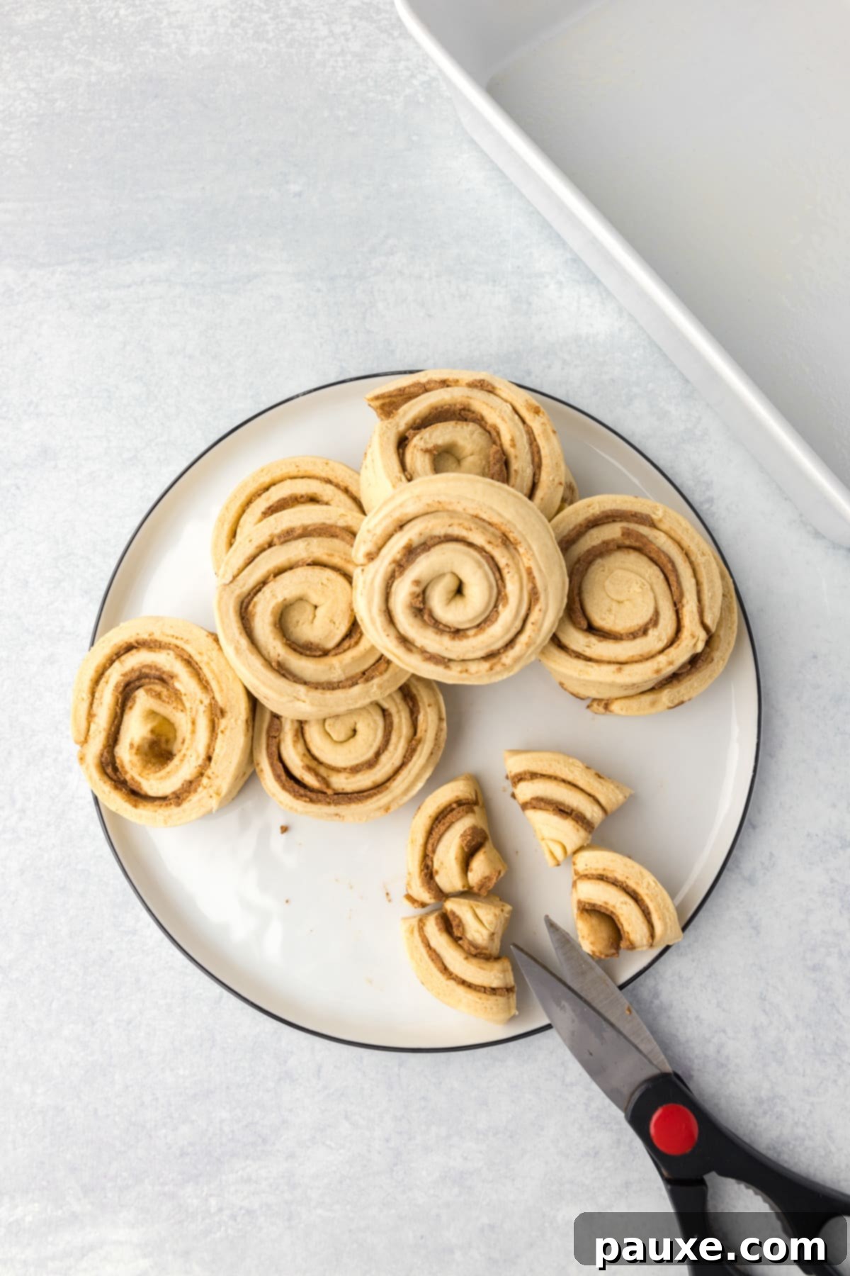Gooey Cinnamon Bliss Bake 4 Using kitchen shears to slice refrigerated cinnamon rolls into quarters.