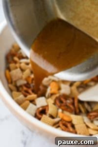 Savory Goldfish Crunch Mix 19 Pouring butter and seasonings over a dry snack mix in a large bowl.
