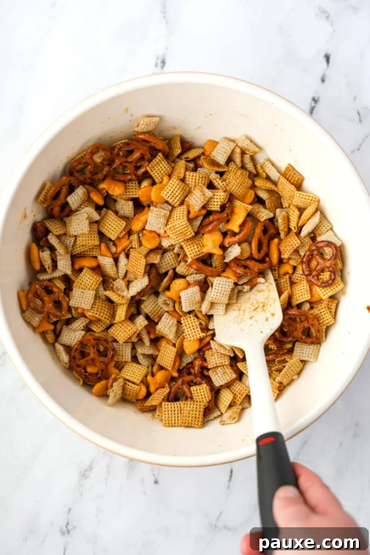 Savory Goldfish Crunch Mix 8 Mixing together a homemade snack mix in a large bowl.
