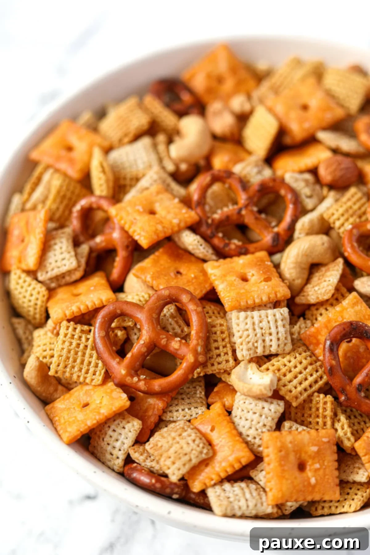 Savory Snack Medley 2 A bowl of savory snack mix with cereal, crackers, and pretzels, perfect for parties.