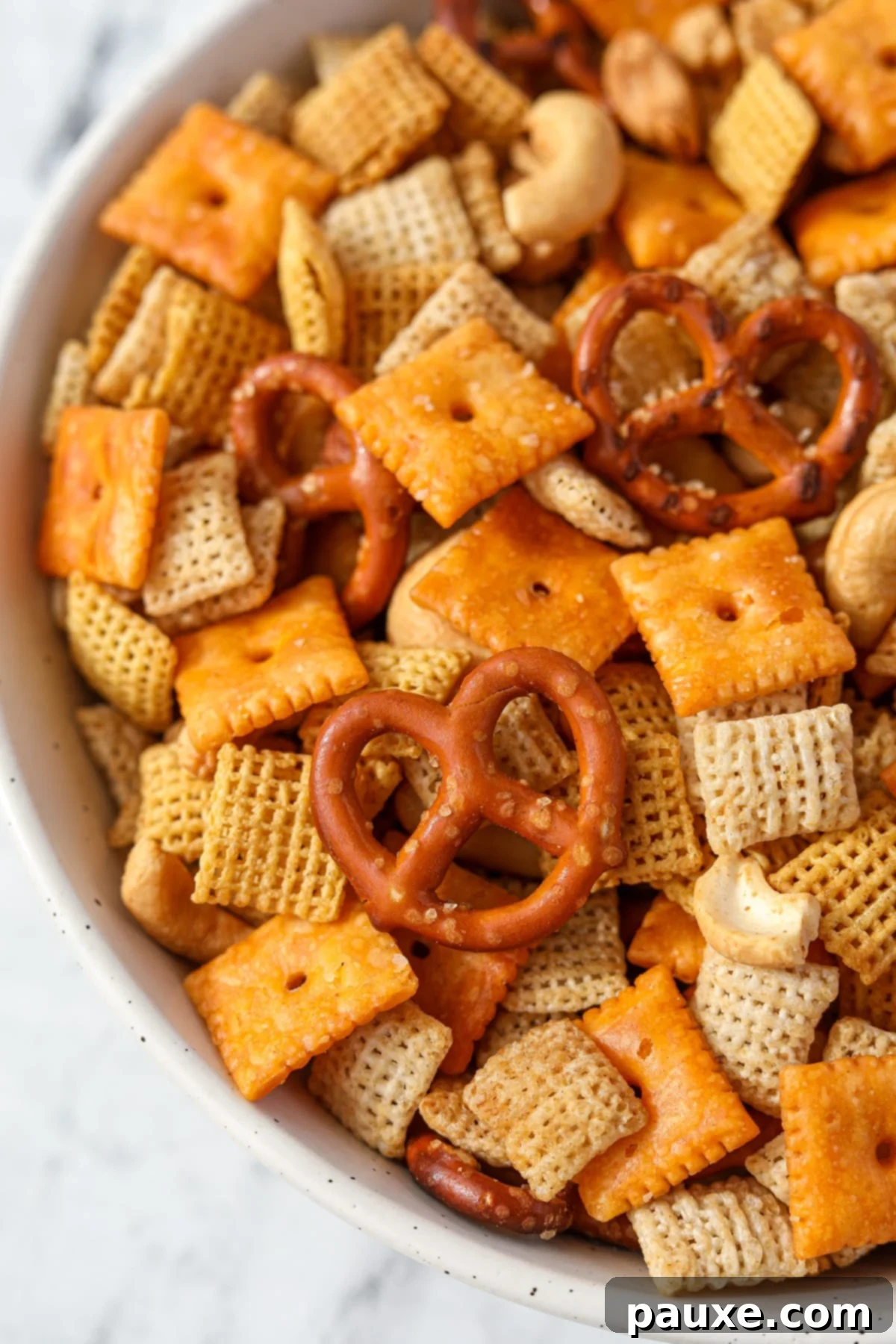 Savory Snack Medley 11 An overhead view of a colorful bowl of homemade Chex Mix, featuring a generous assortment of pretzels, crackers, cereal, and mixed nuts.