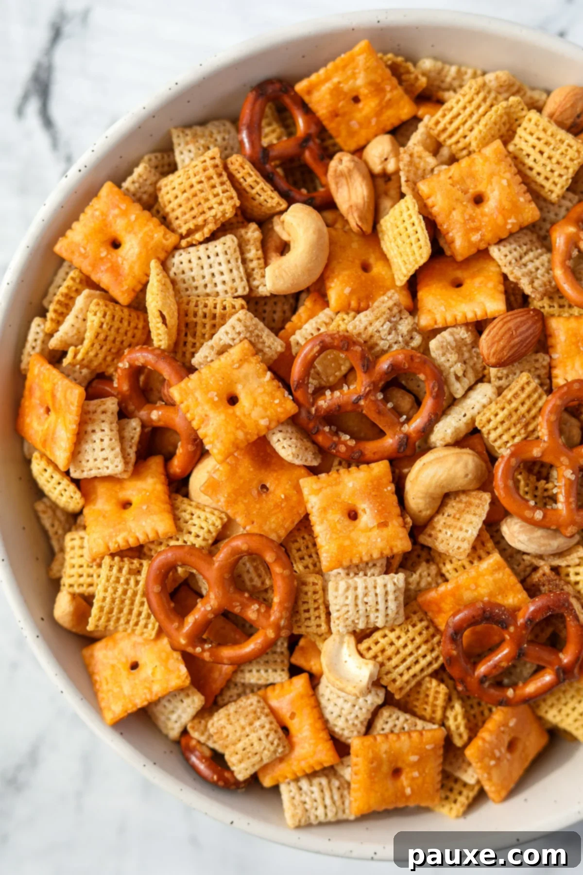 Savory Snack Medley 13 An overhead shot of a vibrant bowl of homemade snack mix, brimming with pretzels, various cereals, crunchy nuts, and savory cheese crackers.