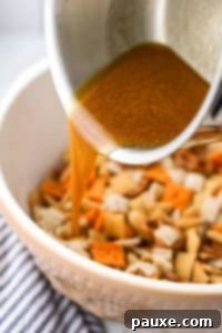 Savory Snack Medley 18 Pouring melted butter into a bowl of snack mix ingredients.