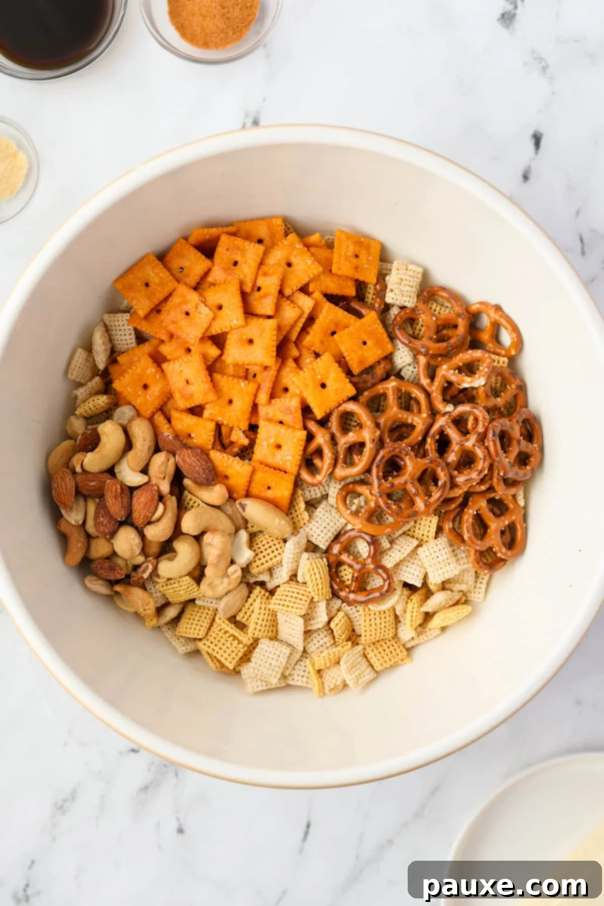 Savory Snack Medley 4 A bowl filled with a variety of Chex cereals, cheese crackers, pretzels, and mixed nuts, ready for seasoning.