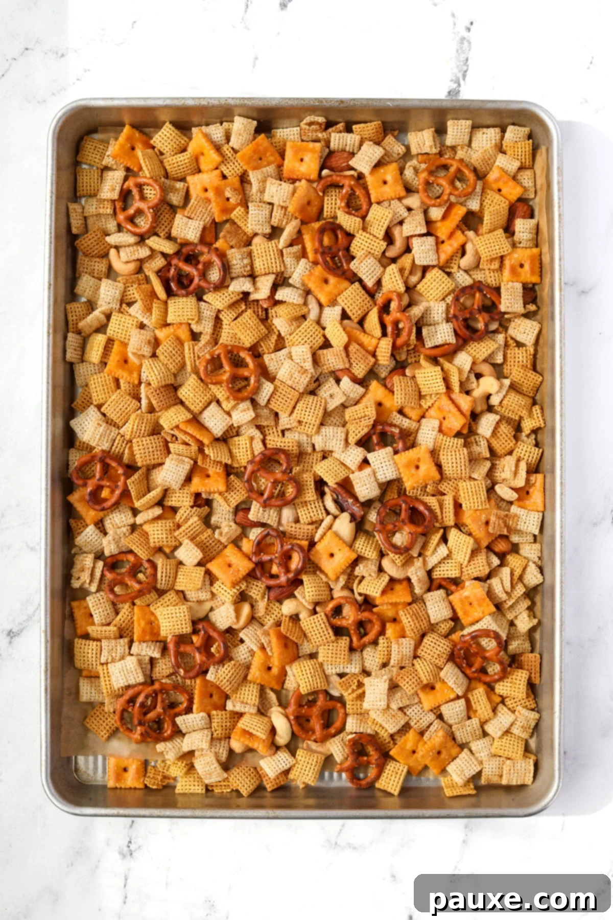 Savory Snack Medley 8 A baking sheet generously filled with savory snack mix, featuring pretzels, cereal, and crackers, spread evenly.