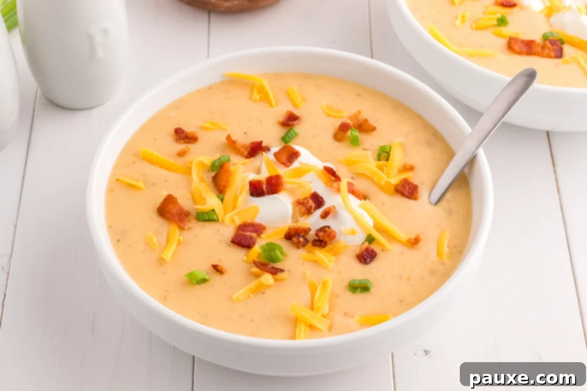 A comforting bowl of baked potato soup with a creamy texture, on a white shiplap dining table.