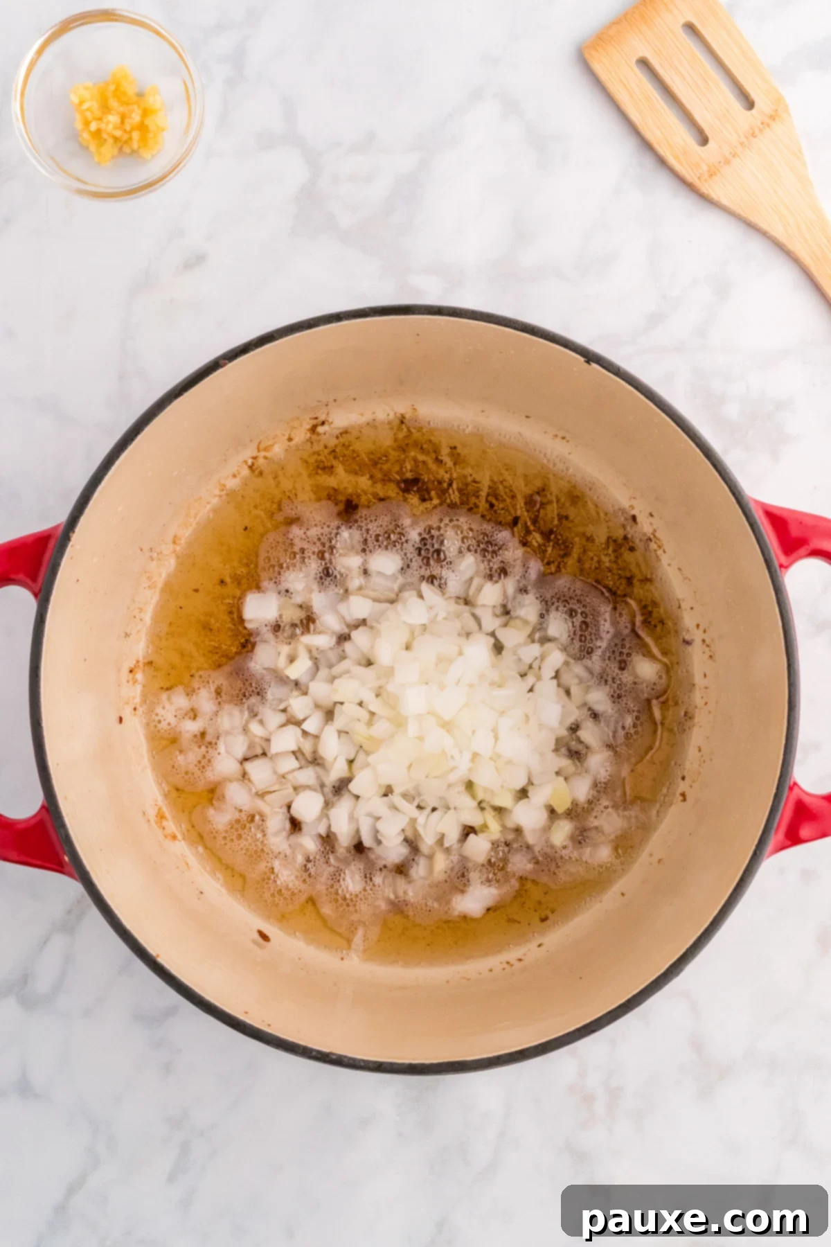 Diced onions sautéing in bacon drippings in a Dutch oven.