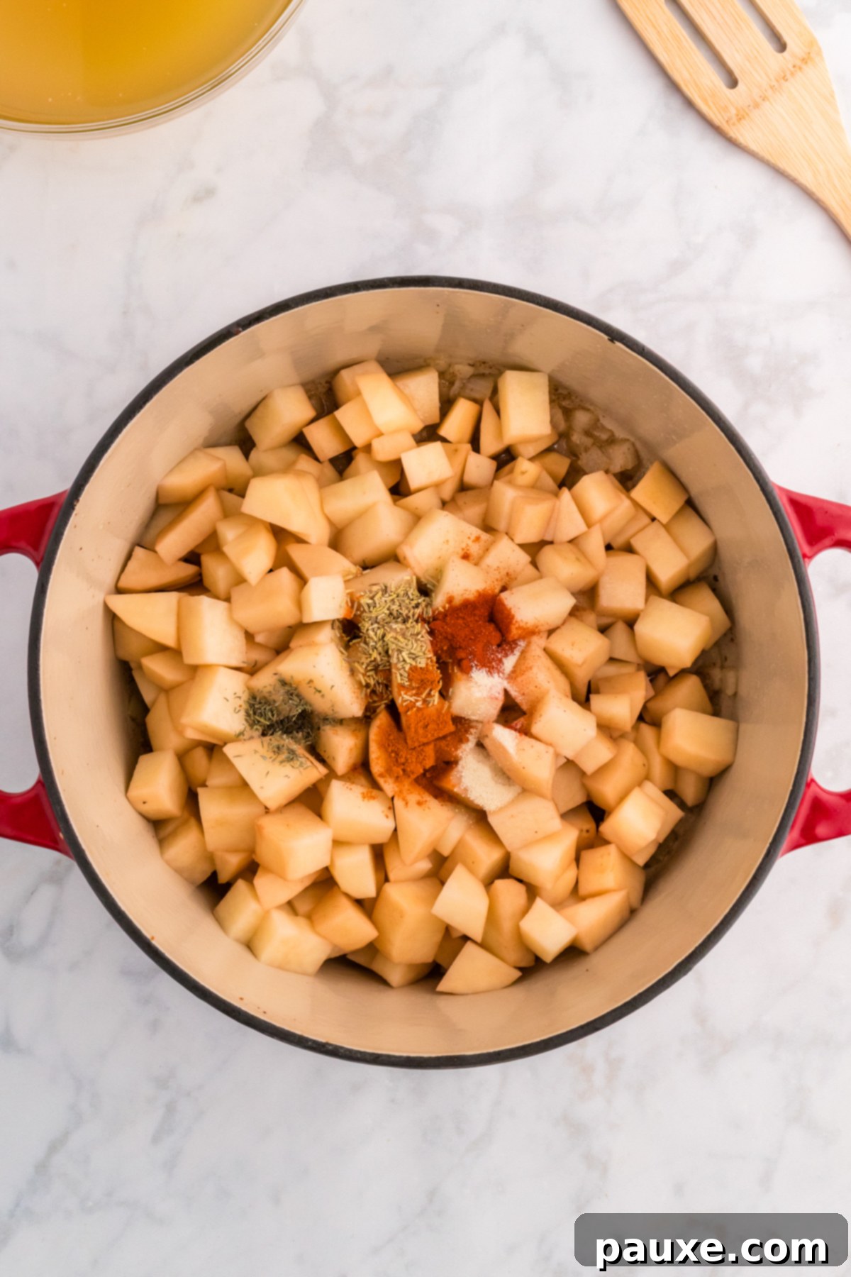 Cubed potatoes being tossed with spices in a Dutch oven.