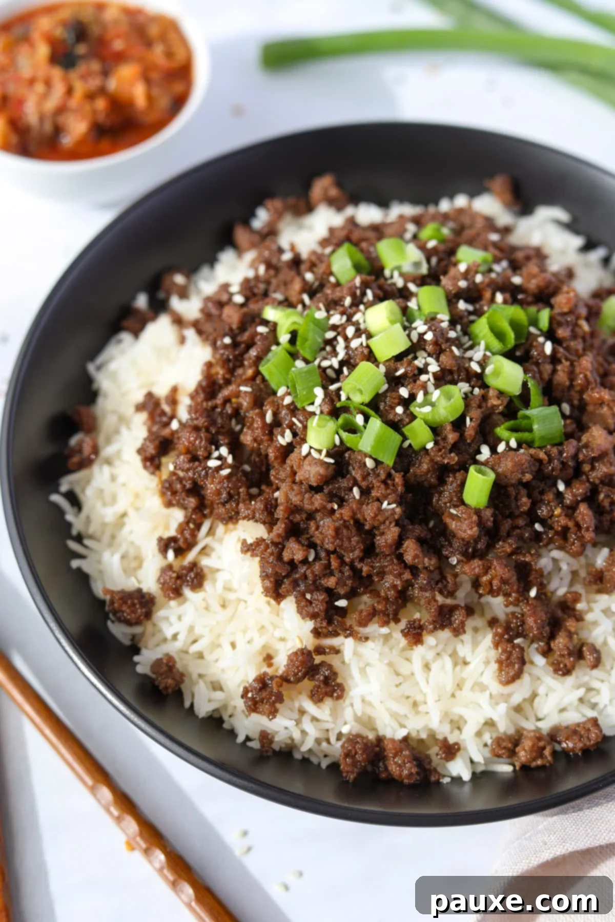 Authentic Korean Marinated Beef 11 A perfectly portioned bowl of Korean ground beef and rice, garnished with green onions and sesame seeds, ready for a satisfying meal.