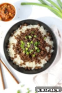 Authentic Korean Marinated Beef 18 A bowl filled with rice and topped with seasoned ground beef, green onions, and sesame seeds.