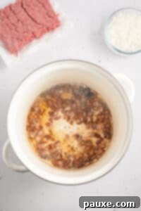 Rancher's Hearty Stew 17 Diced onions cooking in bacon fat within a large pot.