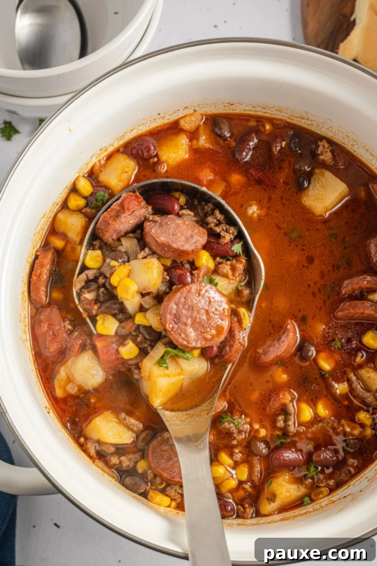 Rancher's Hearty Stew 8 A ladle scooping a generous portion of thick, flavorful Southwestern ground beef stew from a large pot, showing the rich texture and ingredients.